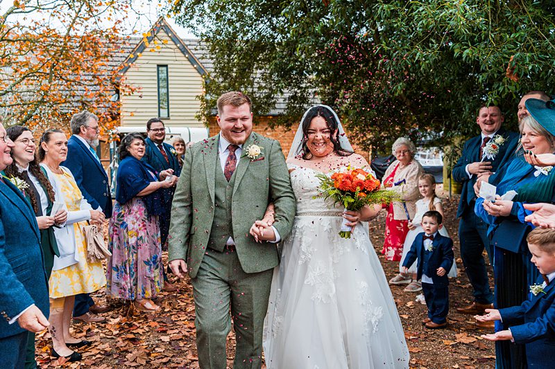 Bride and groom walking through confetti outdoors