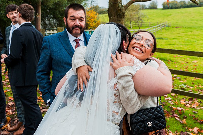 Wedding guests hugging outside on an autumn day.