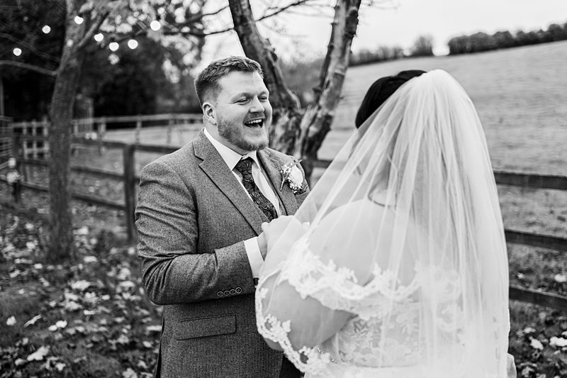 Bride and groom laughing during outdoor wedding ceremony.