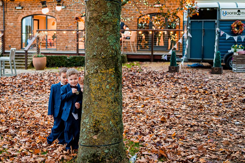 Boys in suits playing hide and seek outdoors.
