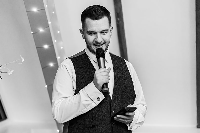 Man in waistcoat speaking into microphone.