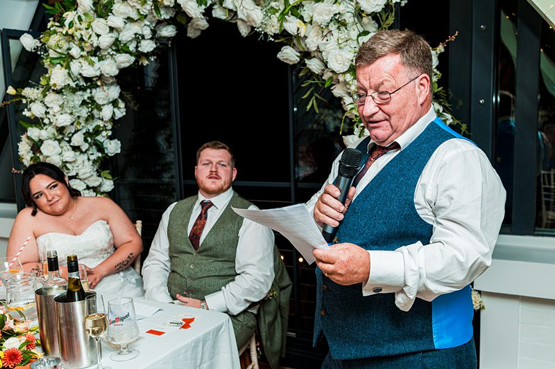 Man giving a speech at wedding reception.