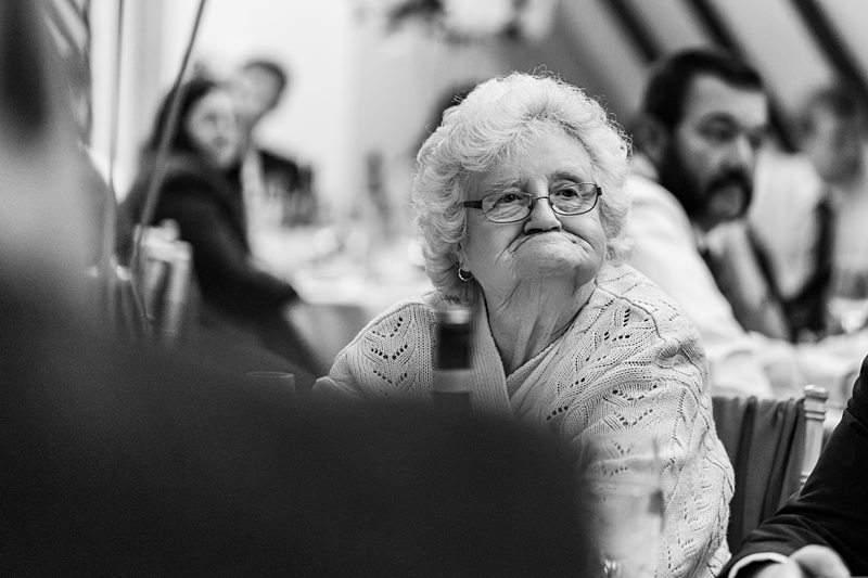 Elderly woman sitting at a formal event.