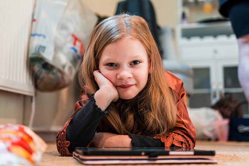 Young girl lying down, smiling indoors.