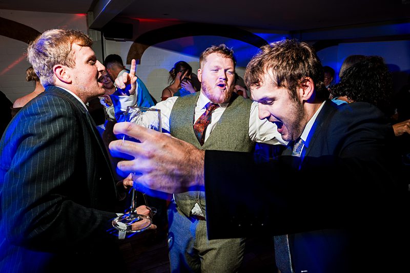 Men celebrating energetically at party with drinks.