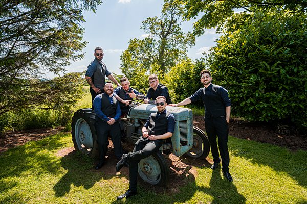 Group of men posing on a vintage tractor outdoors.