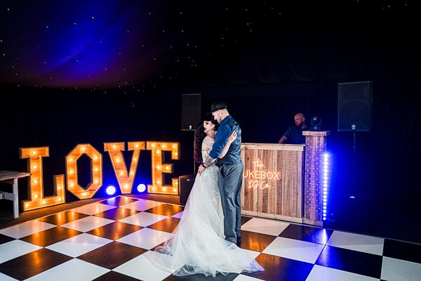 Couple dancing at wedding with large LOVE sign.