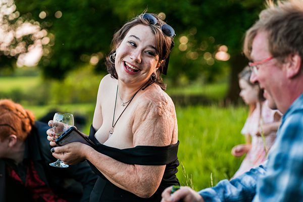 A joyful woman outdoors with friends and drinks.