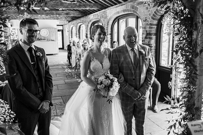 Bride smiling during wedding ceremony with attendees.