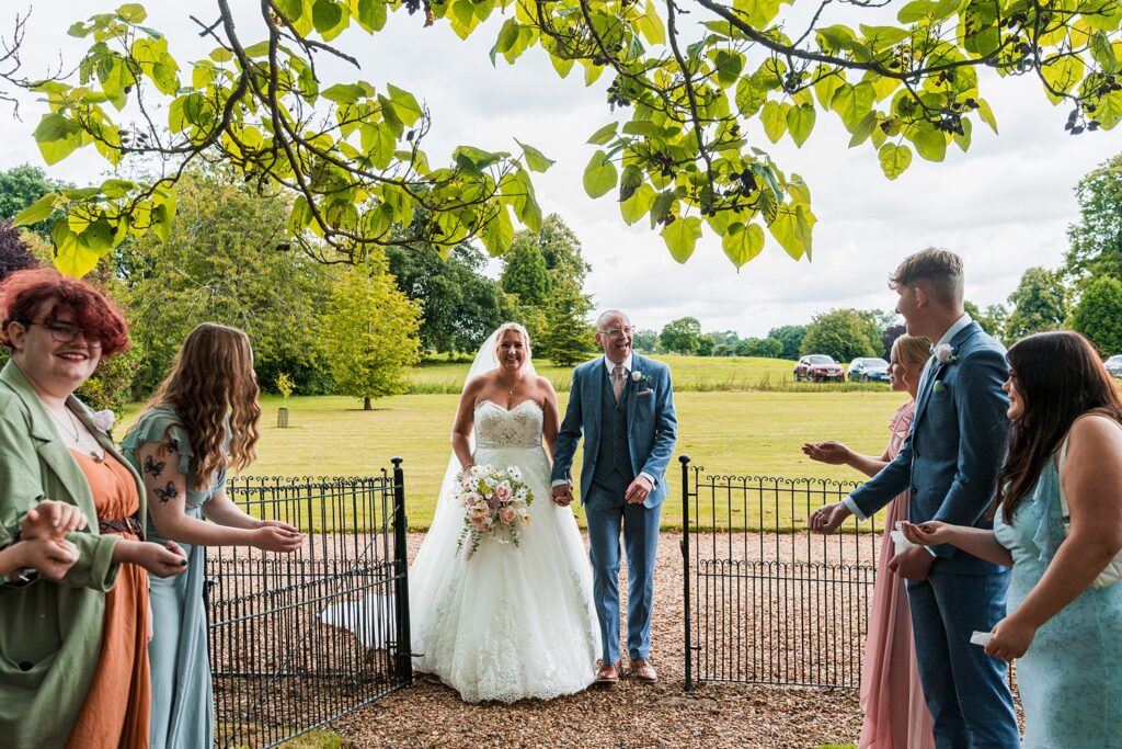 Bride and groom exit ceremony, greeted by guests.