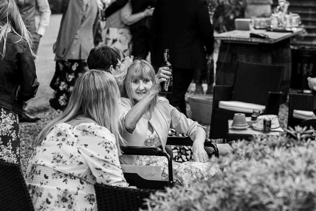 Woman raises bottle in outdoor gathering.