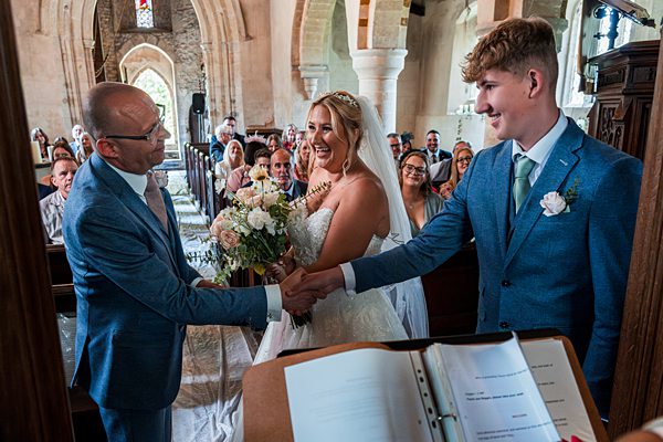 Bride, groom shake hands in church ceremony.
