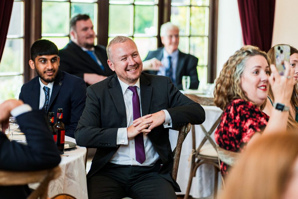 Smiling guests seated at wedding reception.