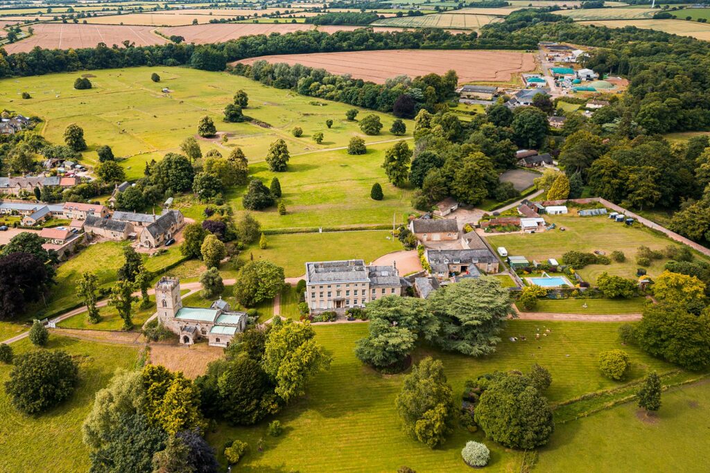 Aerial view of historic countryside estate and gardens.