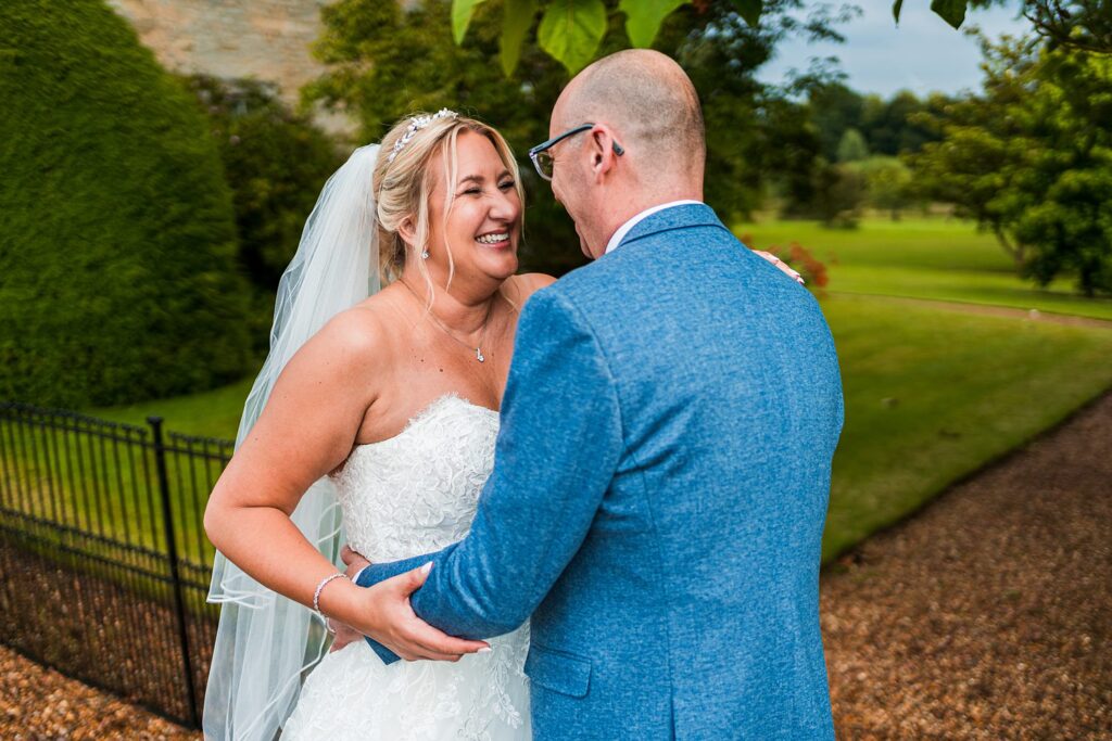 Bride and groom smiling in a garden setting.