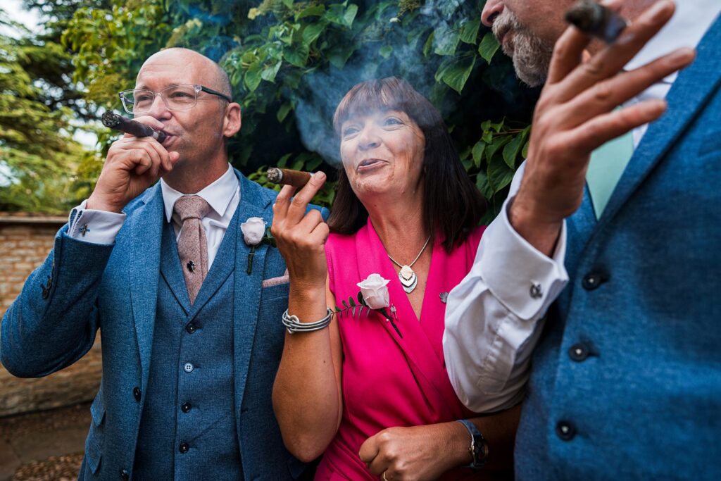 Three people enjoying cigars at outdoor event.