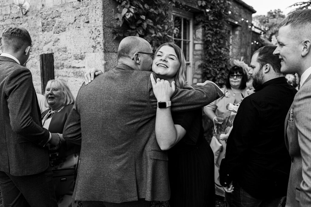 People hugging at outdoor social gathering.