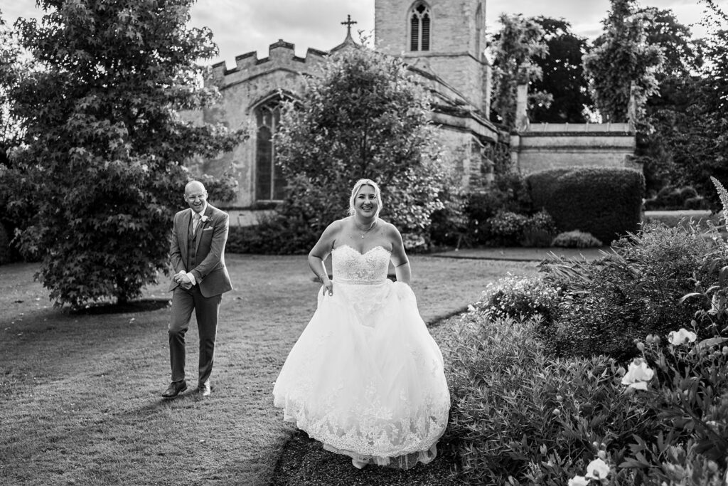 Bride and groom laughing outside church garden.