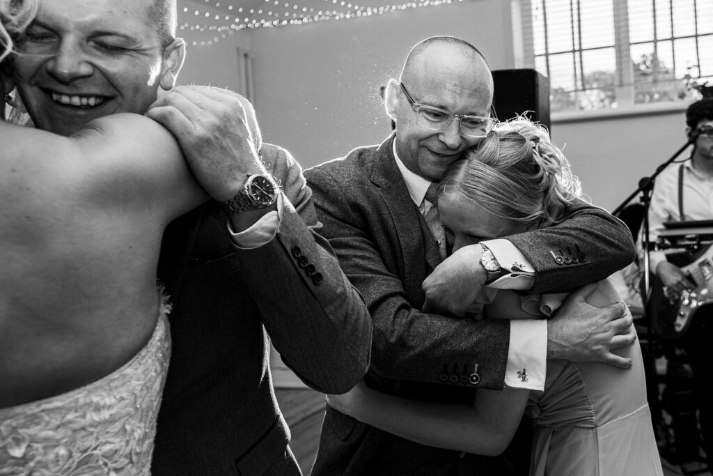 Emotional wedding dance, guests embrace happily.