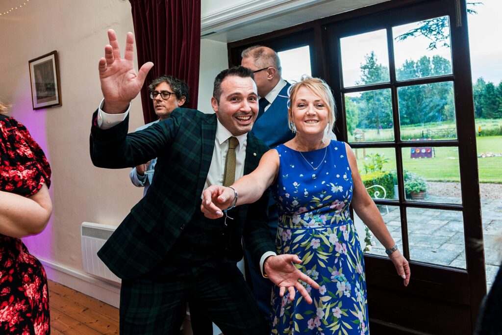 People laughing and dancing at indoor party.
