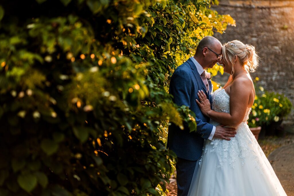 Couple embracing in garden during golden hour.