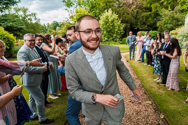 Man in grey suit running joyously at event.
