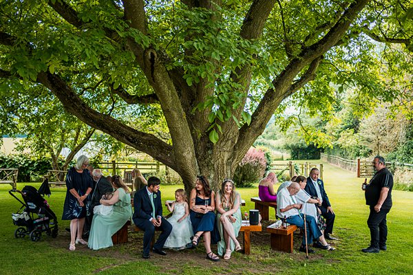 Group of people sitting under a large tree.