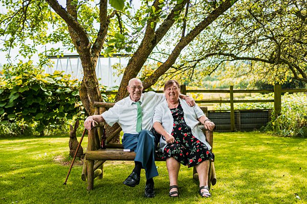 Elderly couple sitting on garden bench.