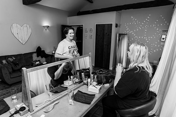 Two women smiling in a hair salon mirror