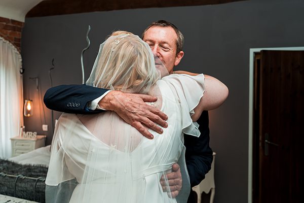 Bride hugging man in emotional wedding moment.