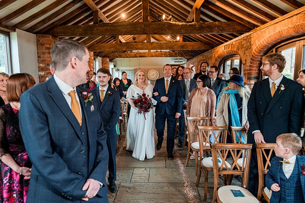 Bride walking down the aisle with guests seated.
