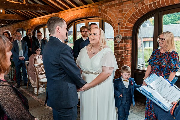 Couple exchanging vows at wedding ceremony indoors.