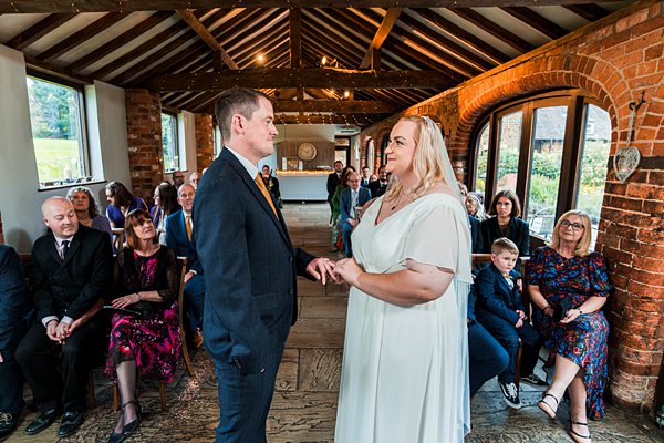 Couple exchanging vows in rustic wedding ceremony setting.