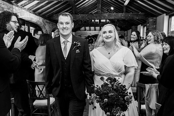 Bride and groom walking down the aisle happily.