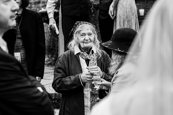 Elderly woman holding champagne at a gathering.