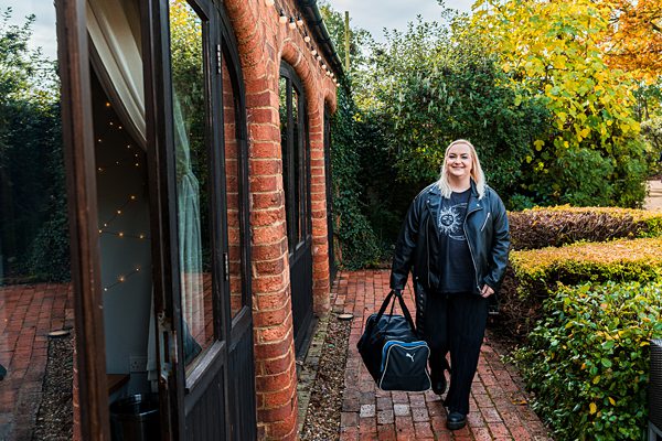 Smiling person arriving at a brick house entrance.