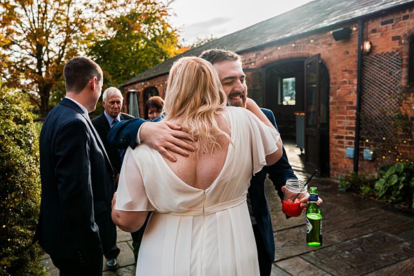 Wedding guests hugging and socialising outdoors.
