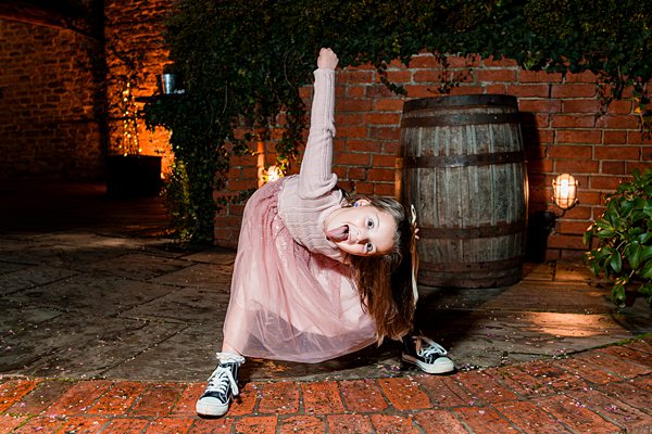 Child dancing, wearing a pink dress and sneakers.