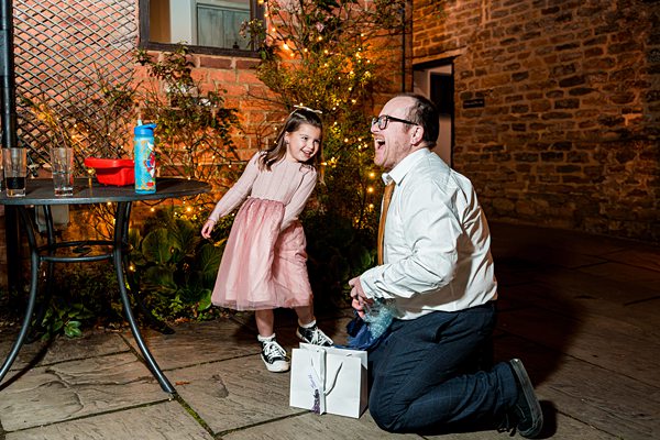 Man and girl laughing outside in evening lights.