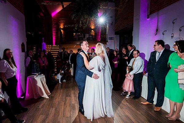 Bride and groom dancing, surrounded by guests.