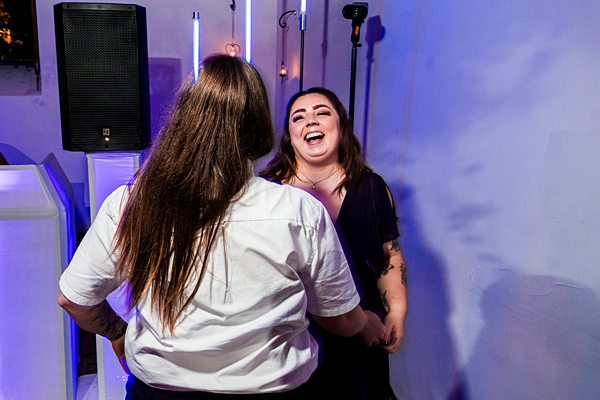 Two women laughing and dancing at a celebration.