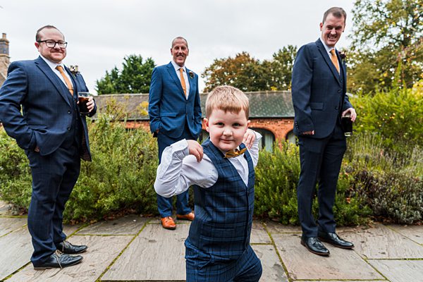 Cheerful child in suit posing with adults outdoors.