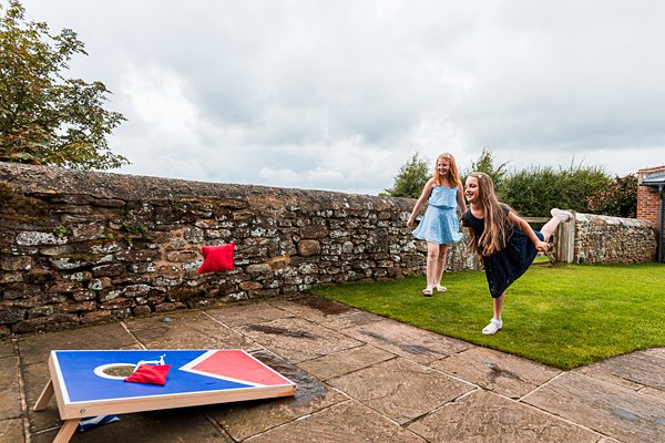 Girls playing cornhole in garden