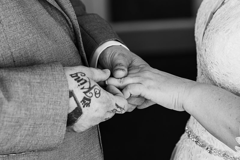 Wedding couple holding hands, exchanging rings.