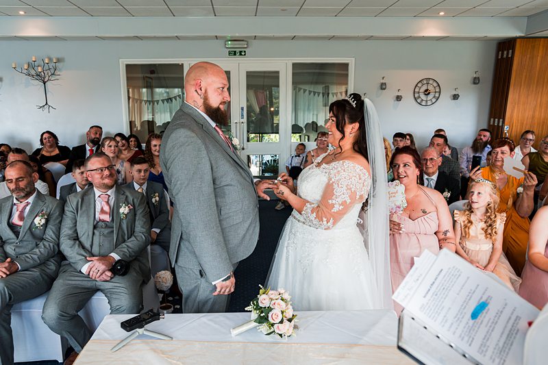 Bride and groom exchanging vows, surrounded by guests.