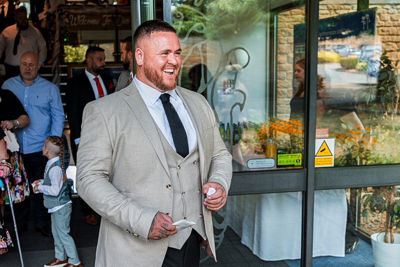 Smiling man in a beige suit outside entrance