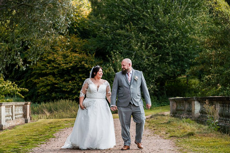 Bride and groom walking hand in hand outdoors.