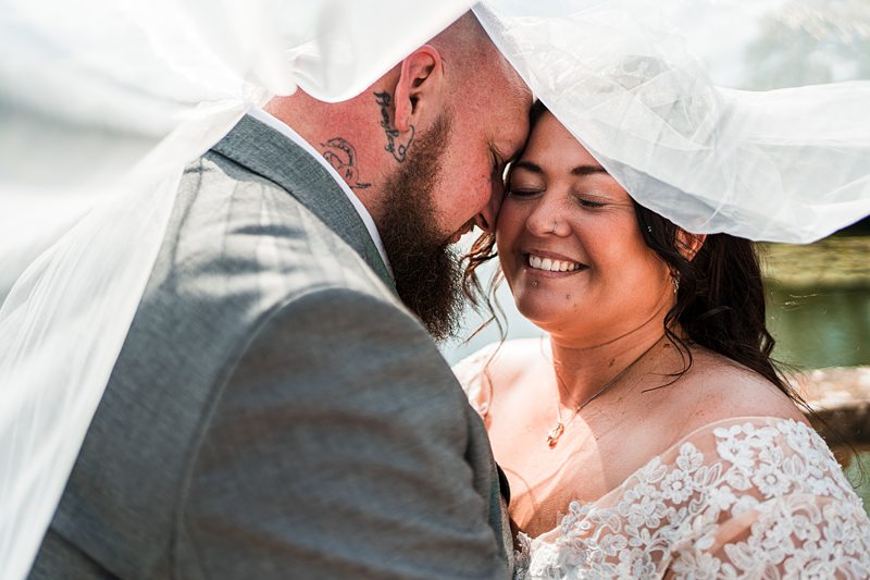 Bride and groom embracing under veil.