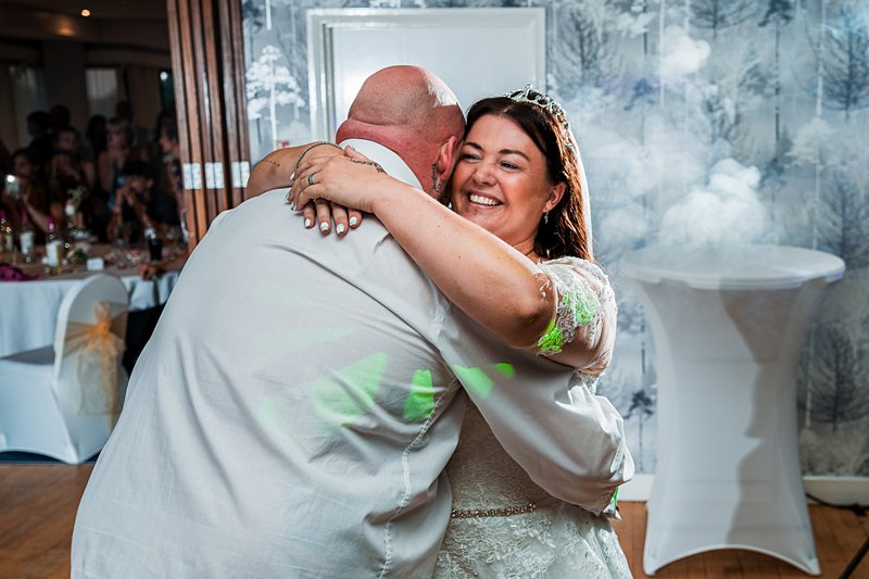 Bride and groom embrace at wedding reception.