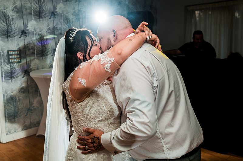 Bride and groom kissing on wedding day dance floor.